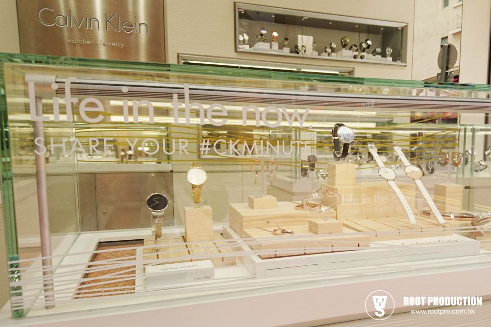 Calvin Klein watch display with watches on wooden stands; light-toned setting.