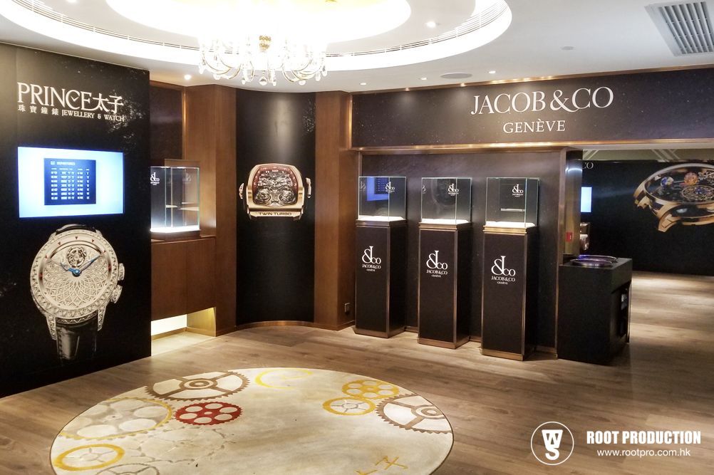 Luxury watch display. Jacob & Co. watches in a high-end store with spotlights, black pillars, and a patterned rug.
