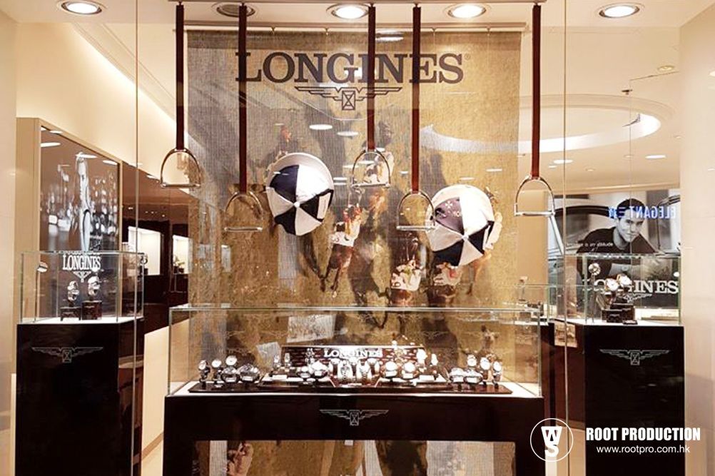 Longines watch display with watches in glass cases, equestrian theme with hanging helmets.