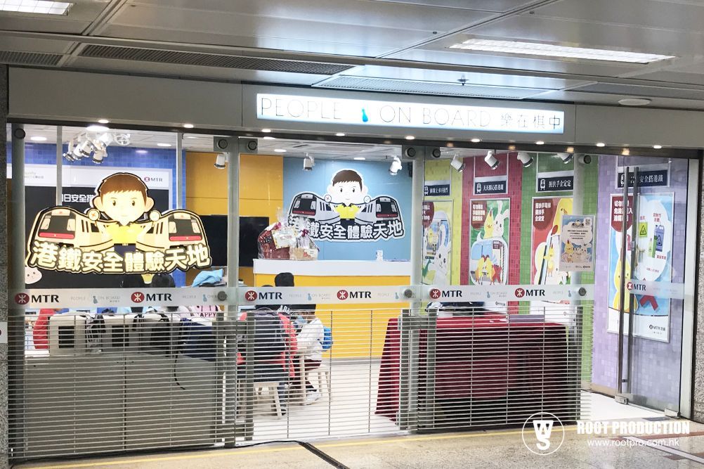 Shop with roll-down gate in Hong Kong subway. Yellow, blue, and white interior with cartoon characters.