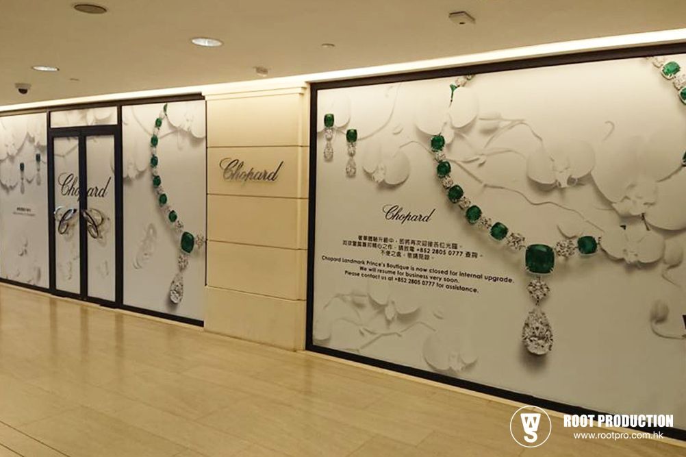Chopard store exterior with jewelry graphic on wall. White, green, and gold colors.  Store sign present.
