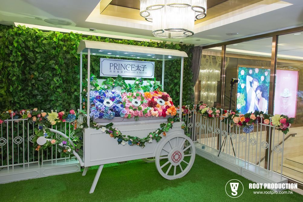White flower cart display with flowers, greenery, and a sign in a venue.