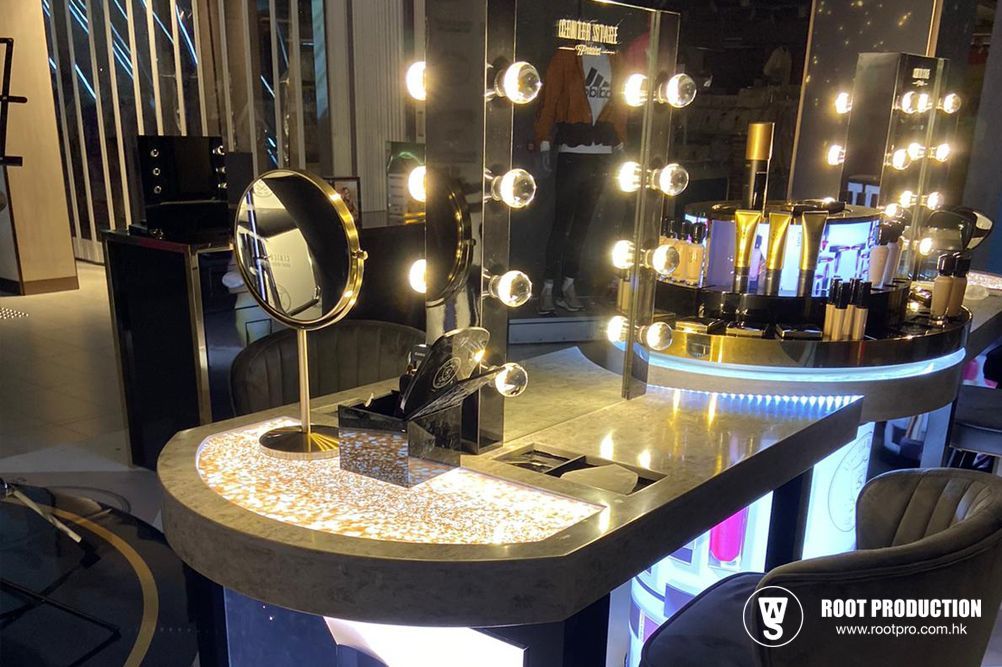 A well-lit makeup counter with products, mirror, and seating in a store.