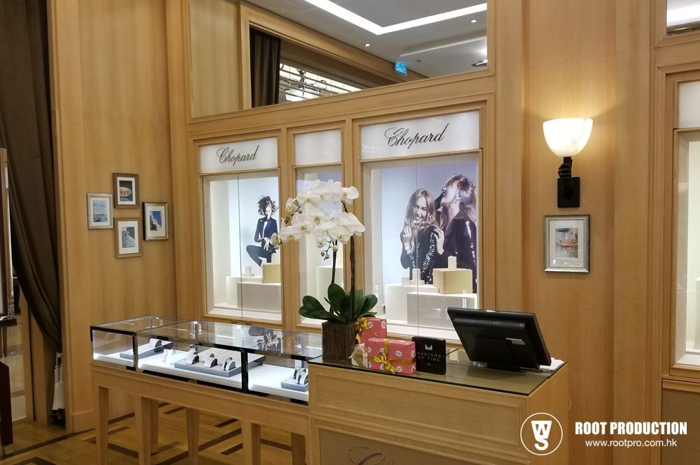 Chopard jewelry store display with watches and floral decorations. Light wood interior with backlit brand signs.