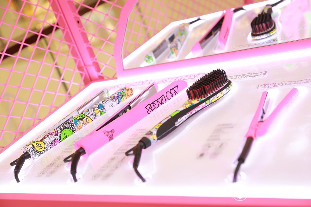Pink hair styling tools on display: brush, straightener, and comb.