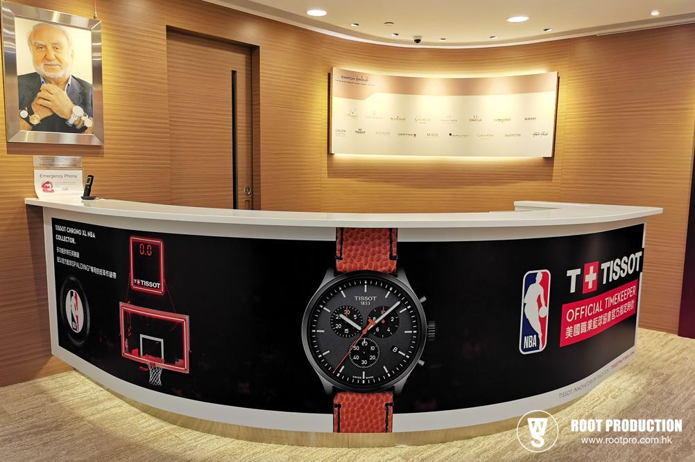 Reception desk featuring a Tissot watch advertisement and a photo of a man. NBA logo visible.