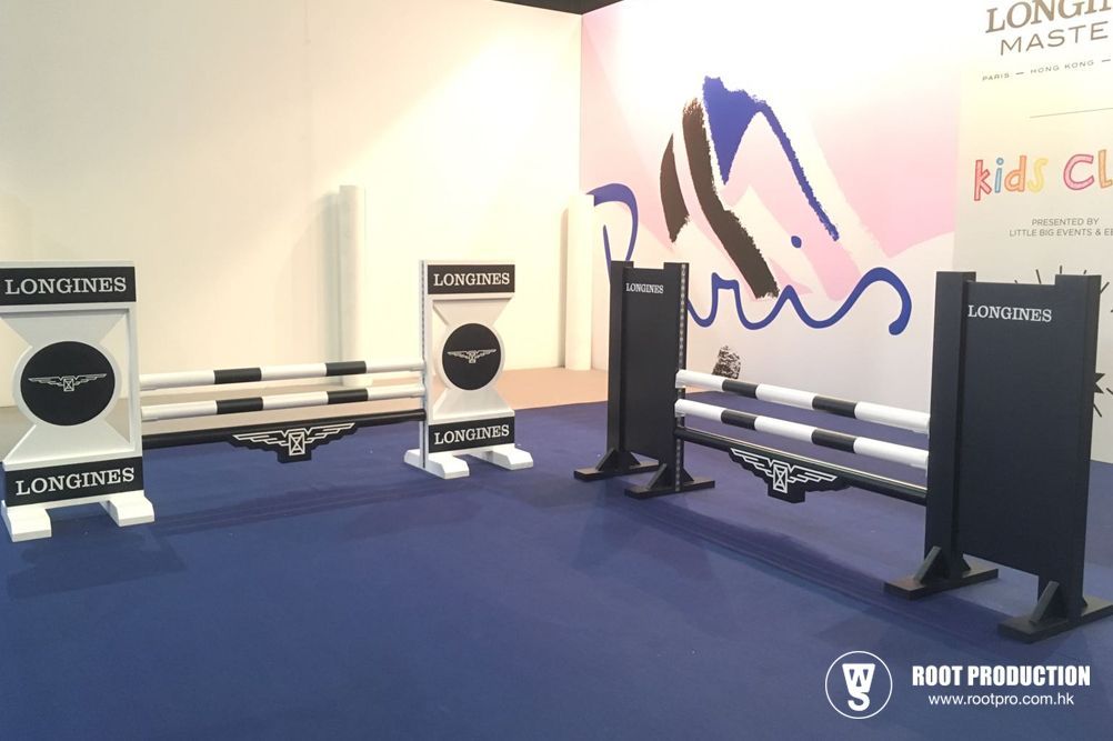 Show jumping course with Longines branding, on blue carpet, at an event with a logo in the background.