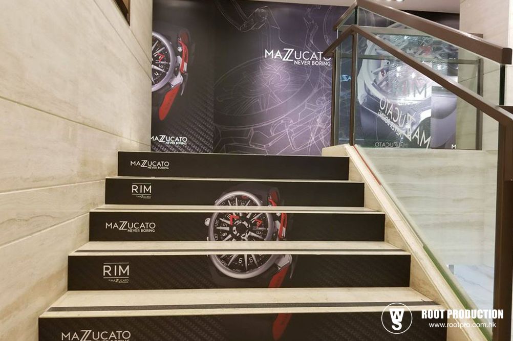 Staircase with watch advertisement, black and red, inside a shop.