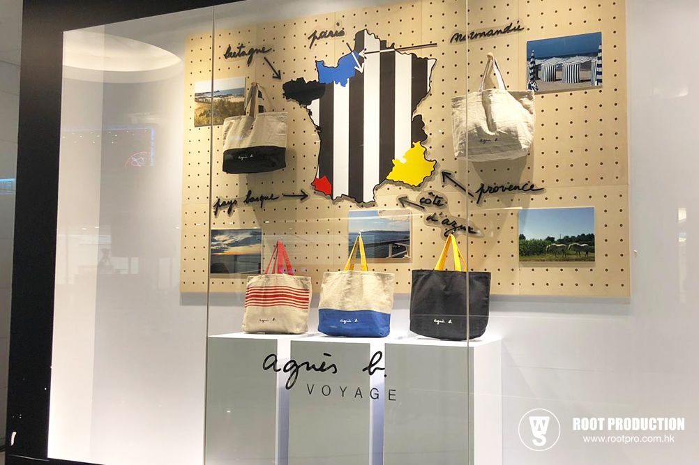 Agnes B Voyage store display with bags, map of France, and photos, on white backdrop.