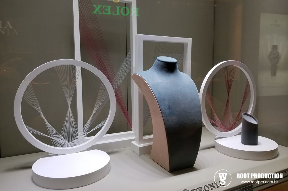 Jewelry display: mannequins, white frames with string art, on a shelf in a store.