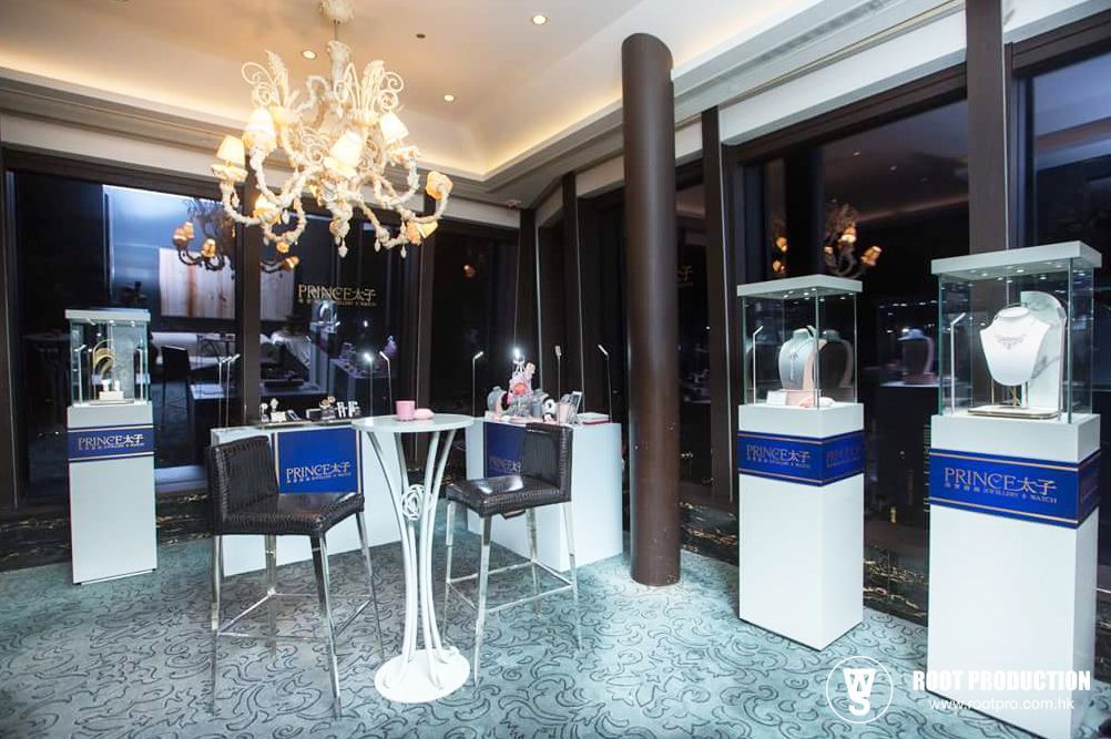 Jewelry display in a room with a chandelier, white display cases, and a table.