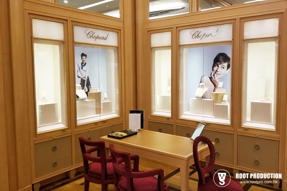 Chopard jewelry display with beige walls, showcases, table, chairs, and two models.