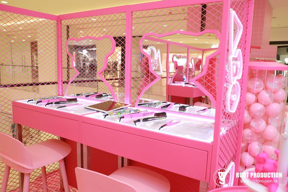 Pink retail display with chairs, toys, and gumball machine in a mall setting.