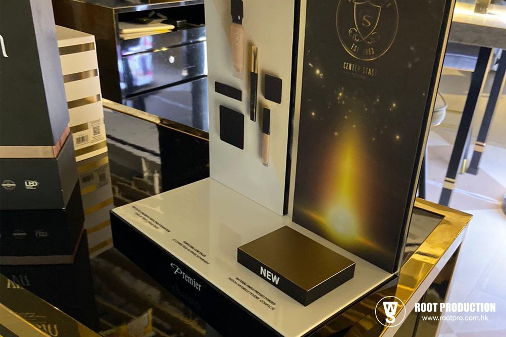 Cosmetics display stand with products, in a store setting. Featuring gold, black, and white.