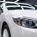 A close-up, angled view of the front passenger side of a clean, shiny white sedan parked in an indoor garage.