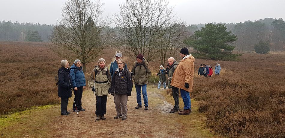 Foto von einer Heidelandschaft mit Leute von unserem Verein drauf. Die Bäume sind ohne Blätter, da es Winter ist. Entsprechend auch die Kleidung der Leute.