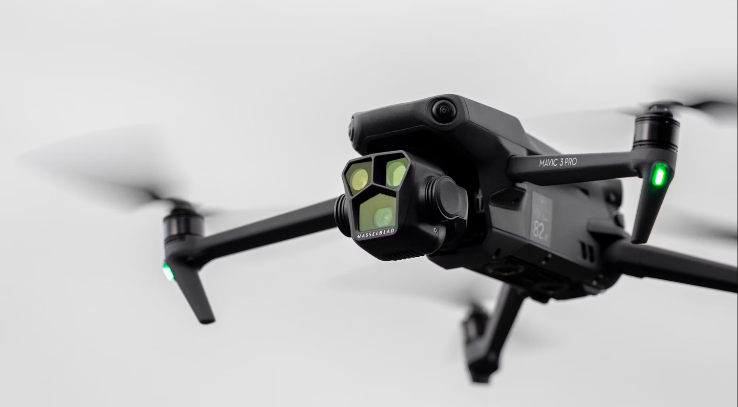 A black drone is flying in the air with a white background.
