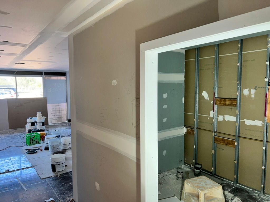 A Man is Kneeling Down in a Room With a Ladder — Poljak Plasterers in Rosslea, QLD