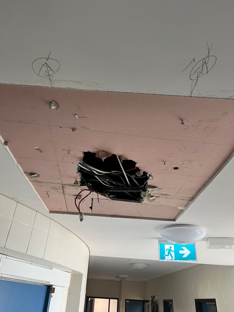 A Long Hallway With a Wooden Floor and White Walls — Commercial Plasterers in Townsville