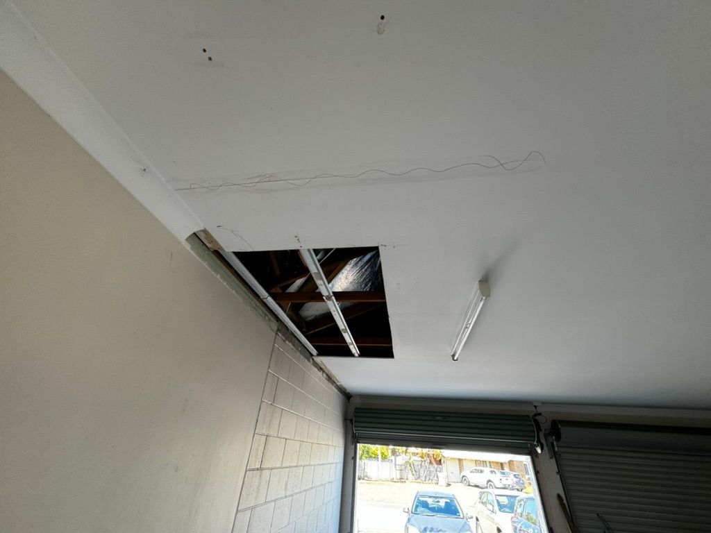 A Man in an Orange Shirt is Plastering a Wall — Poljak Plasterers in Rosslea, QLD