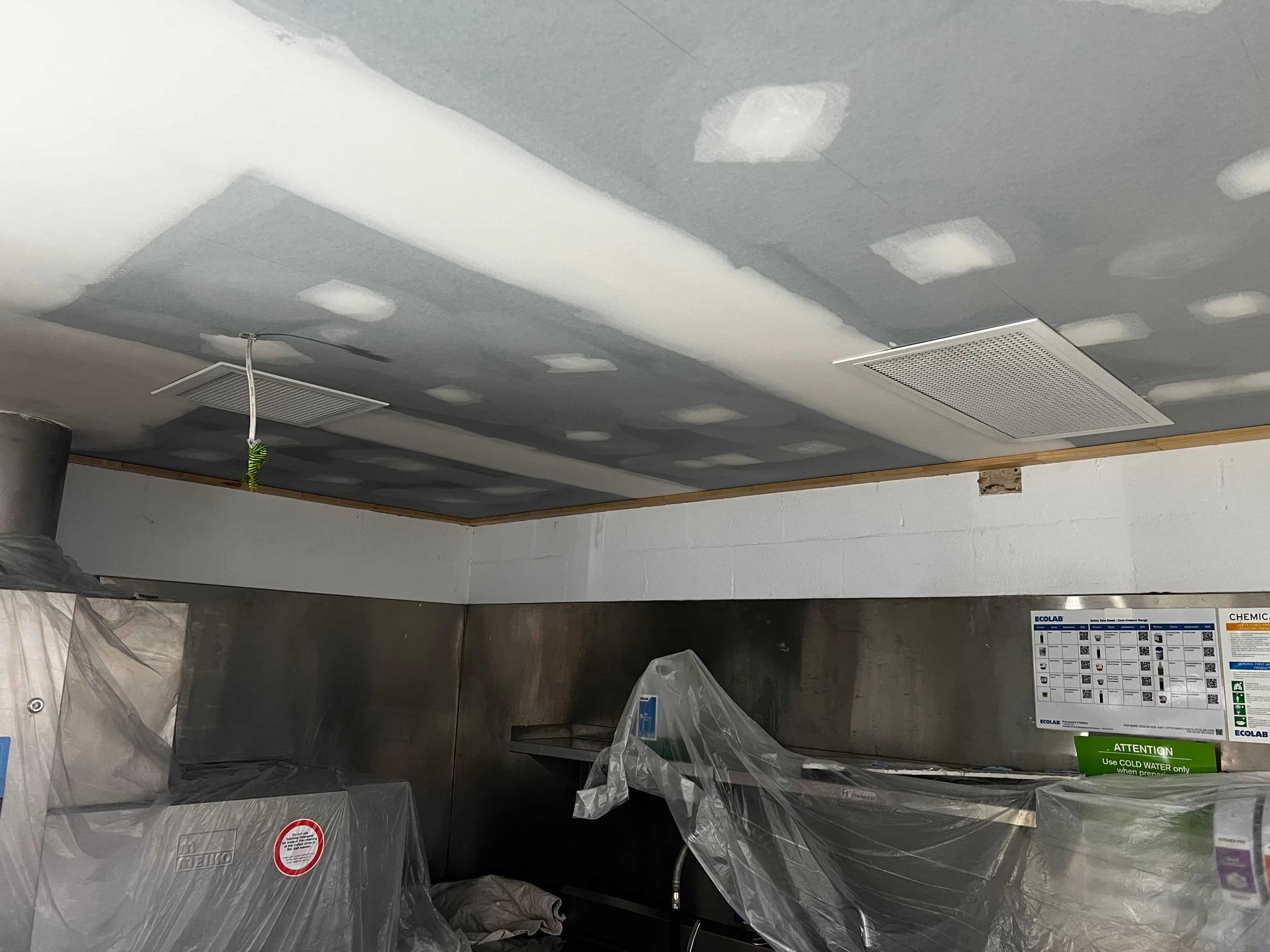 A Kitchen With Stainless Steel Appliances and a Ceiling That is Covered in Plastic — Poljak Plasterers in Cranbrook, QLD