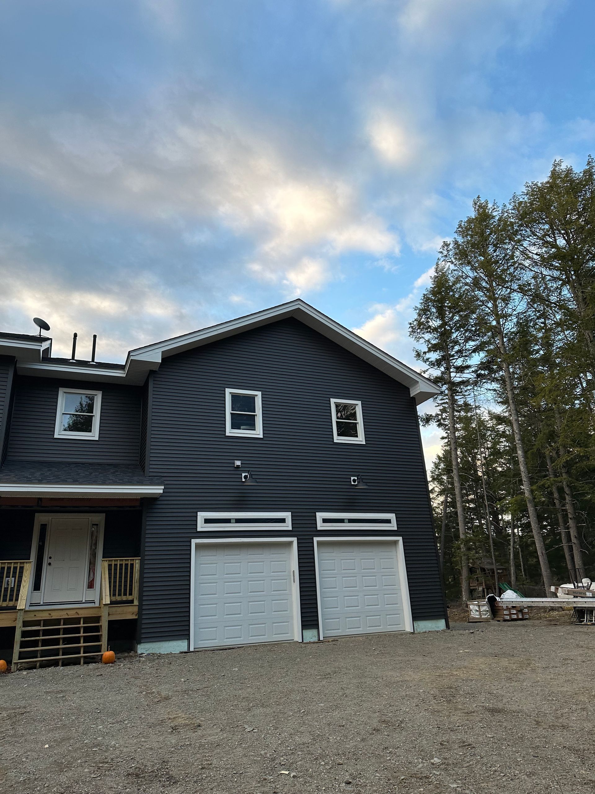 A black house with two garage doors and a blue sky in the background