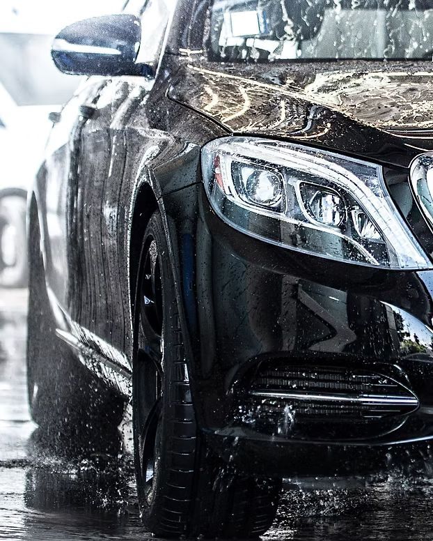 Black car being washed with water, close-up view.
