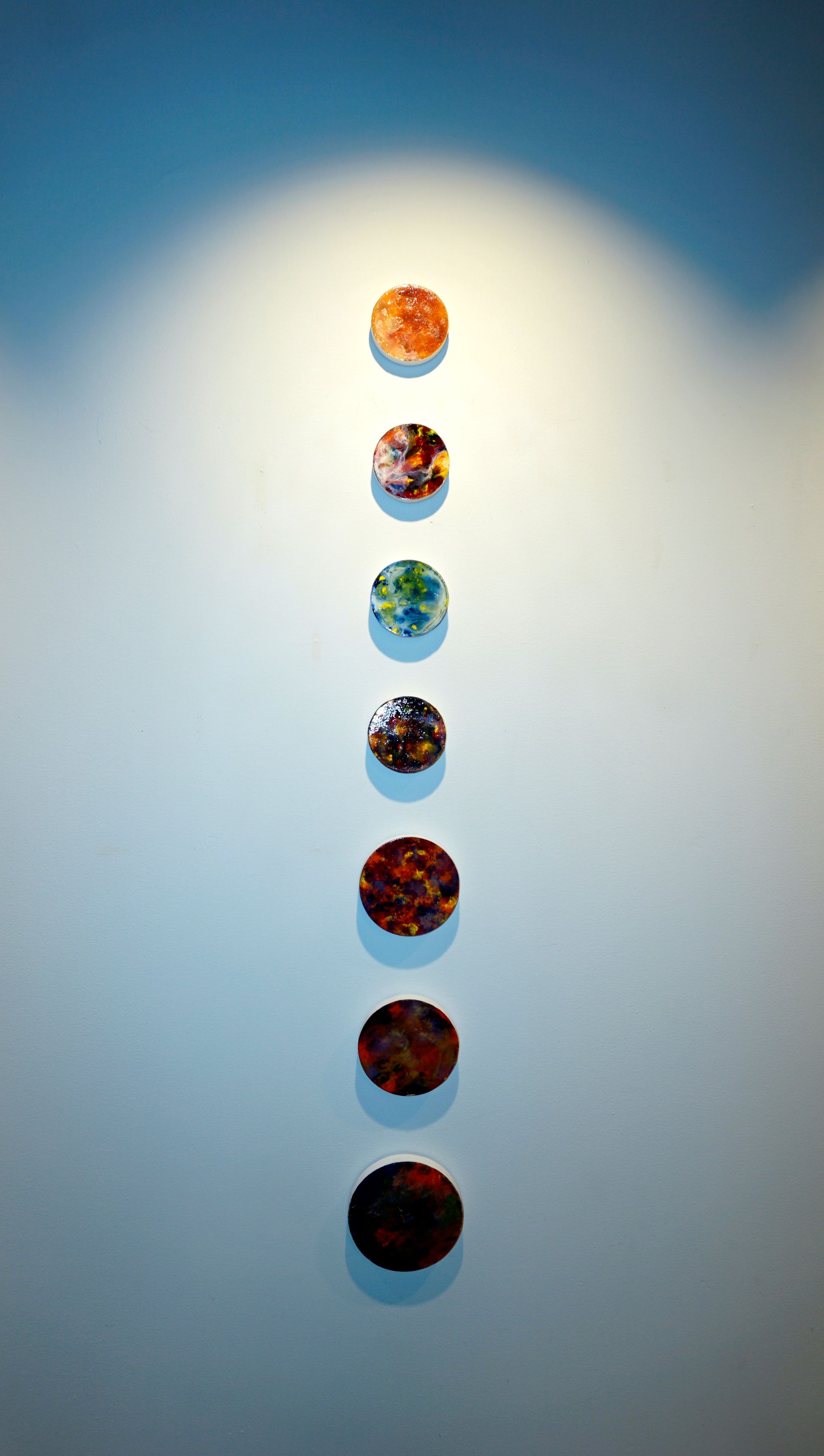 A row of colorful circles are lined up on a wall.