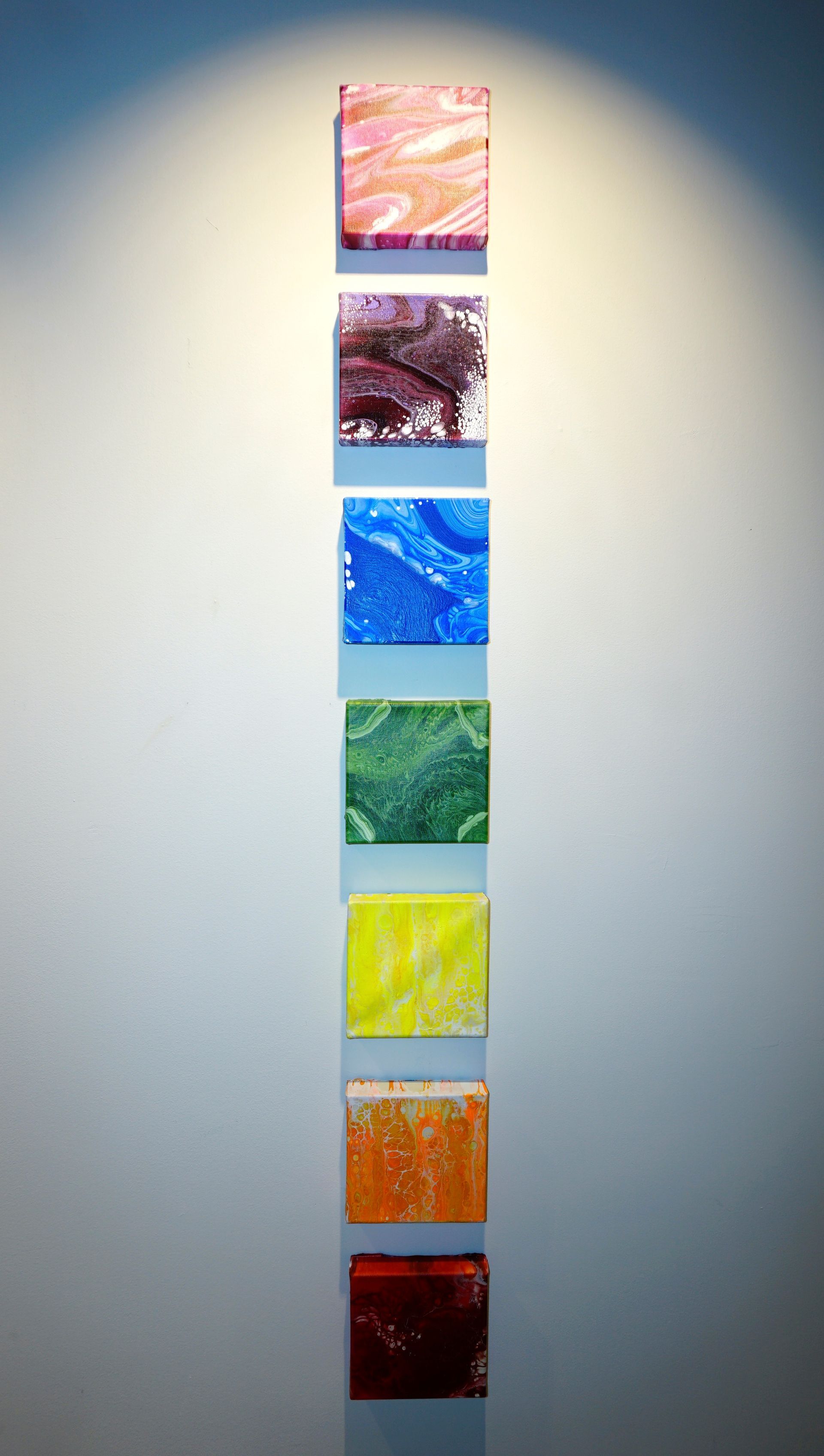 A row of colorful squares are lined up on a wall.