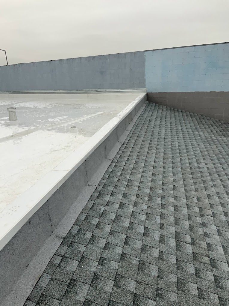 A roof with a gray shingle roof and a white roof.