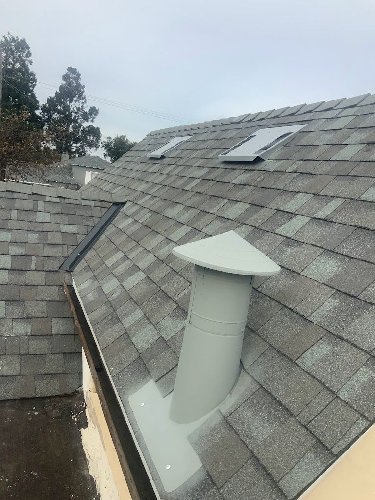 A roof with a chimney and two skylights on it