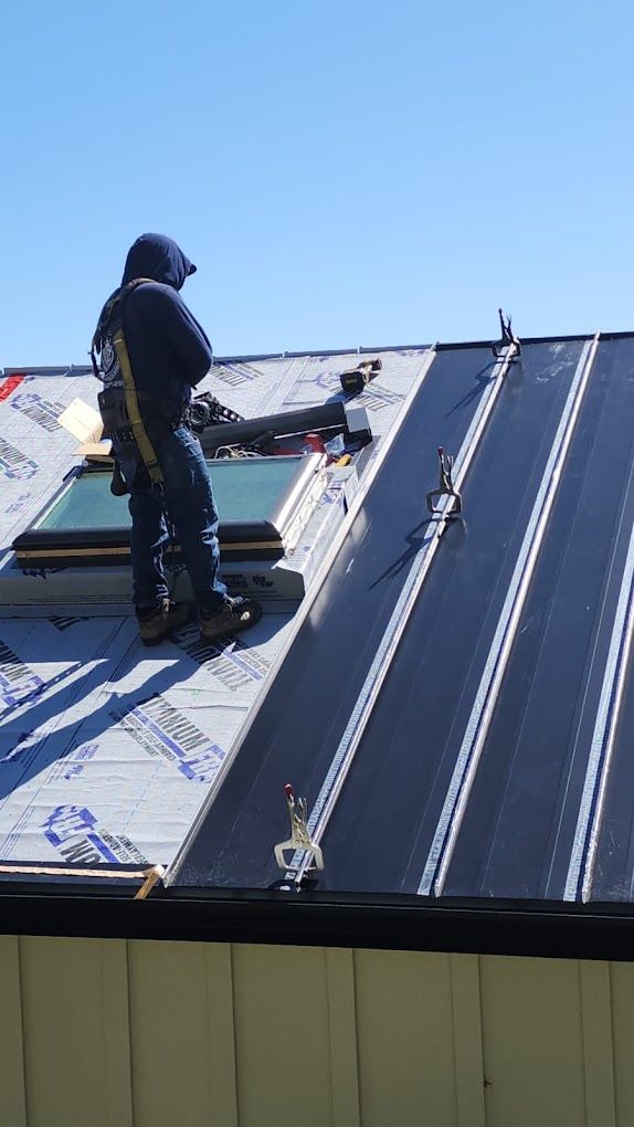 A man is standing on top of a roof working on it.
