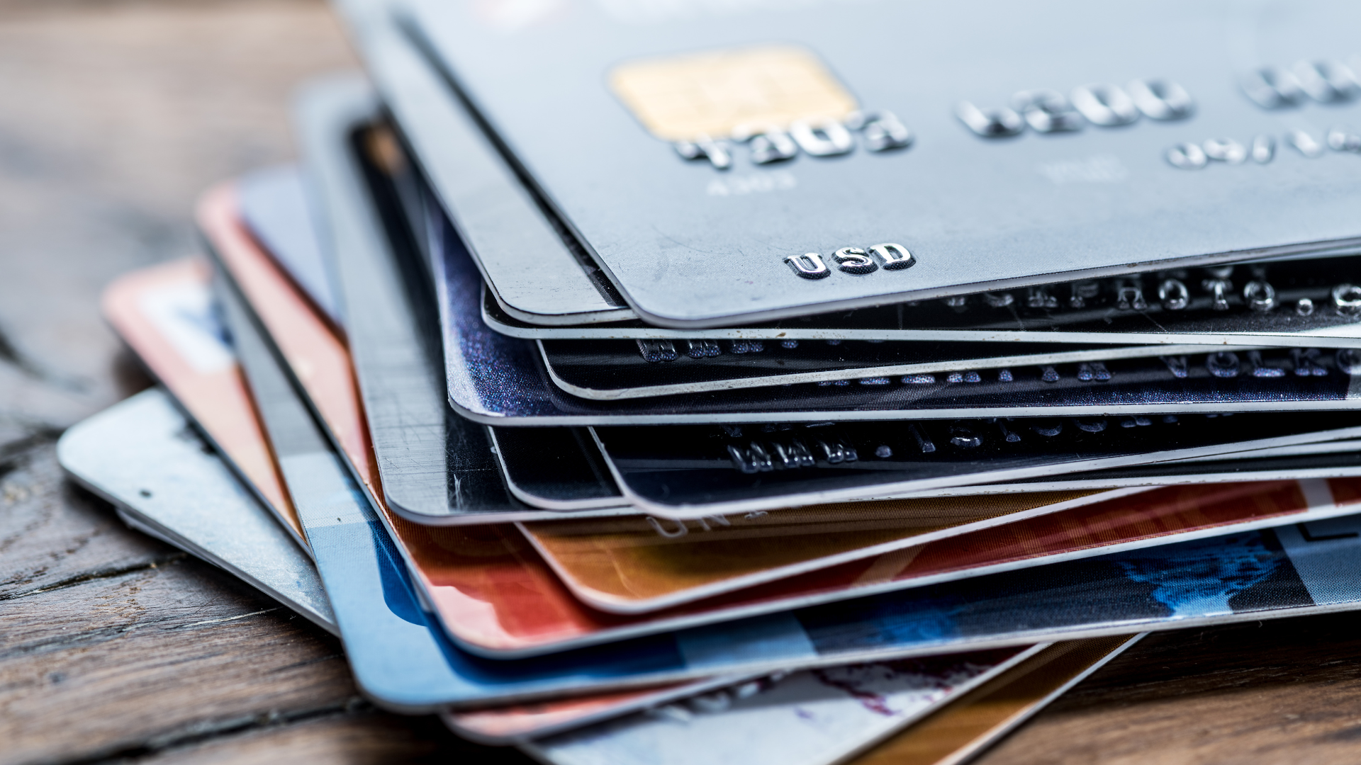 A stack of credit cards sitting on top of each other on a wooden table.