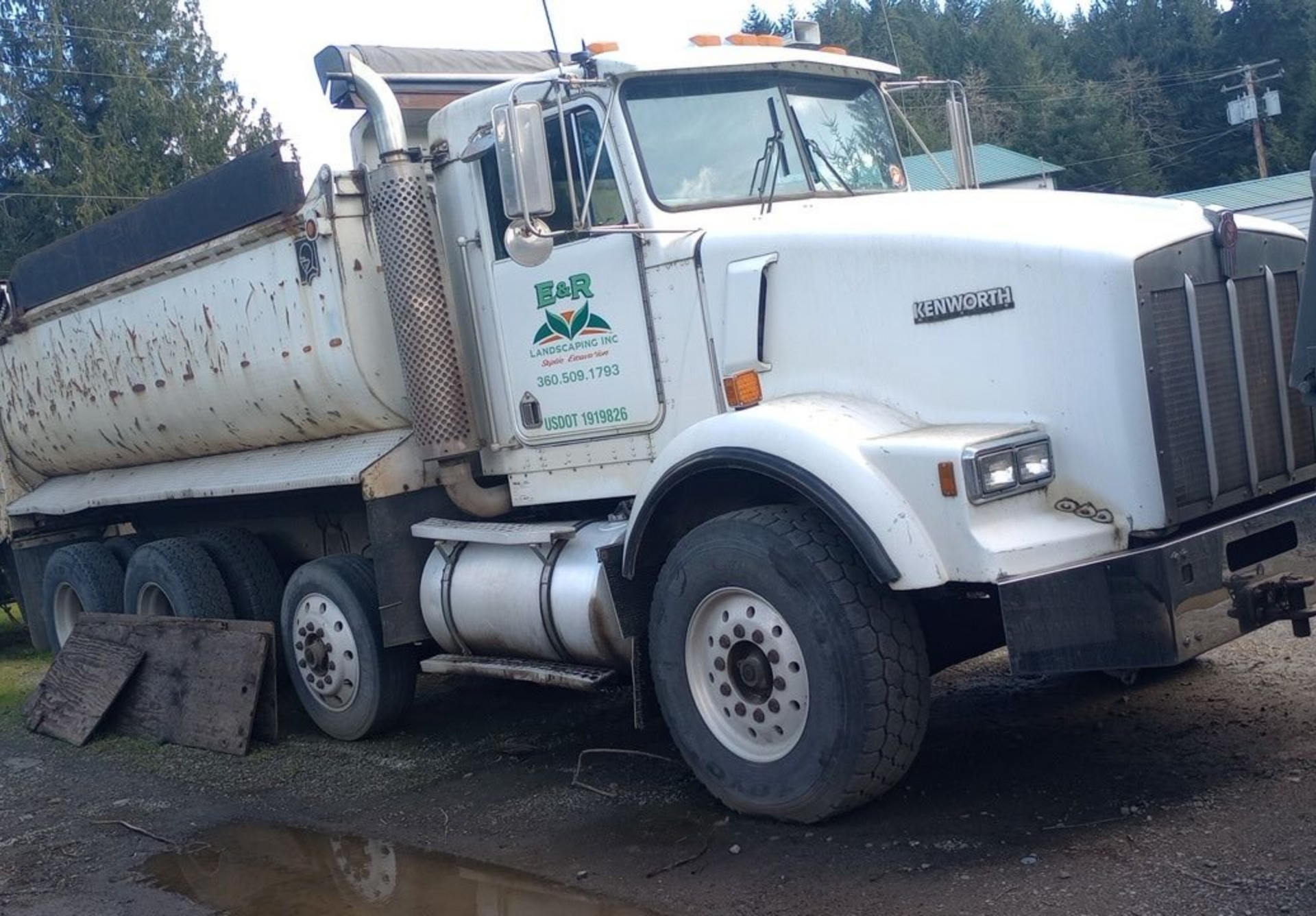 White Kenworth dump truck parked outdoors.