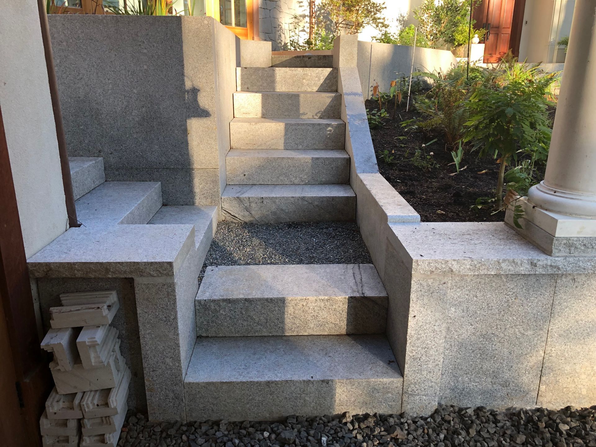 Granite steps leading up to a building, flanked by low walls and gravel.