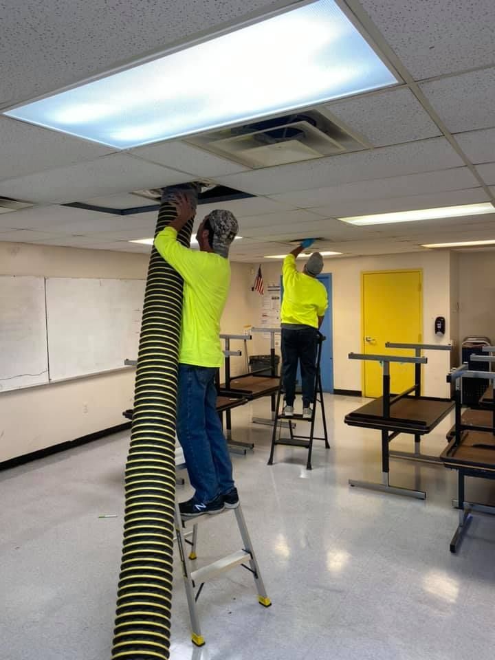 Two men are working on the ceiling of a building