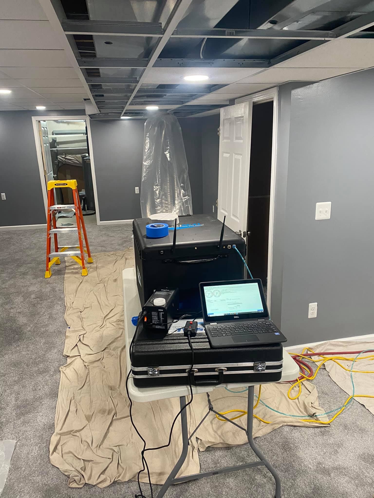 A basement with a ladder and a table with a laptop on it.