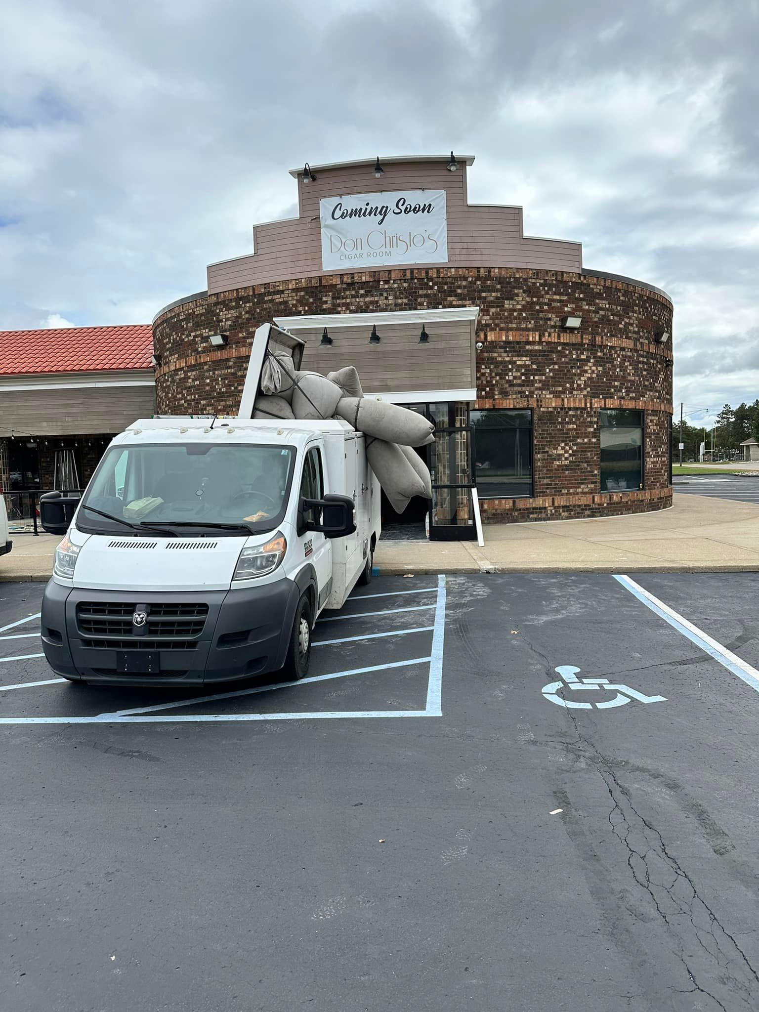 A white van is parked in a handicapped parking spot in front of a building.