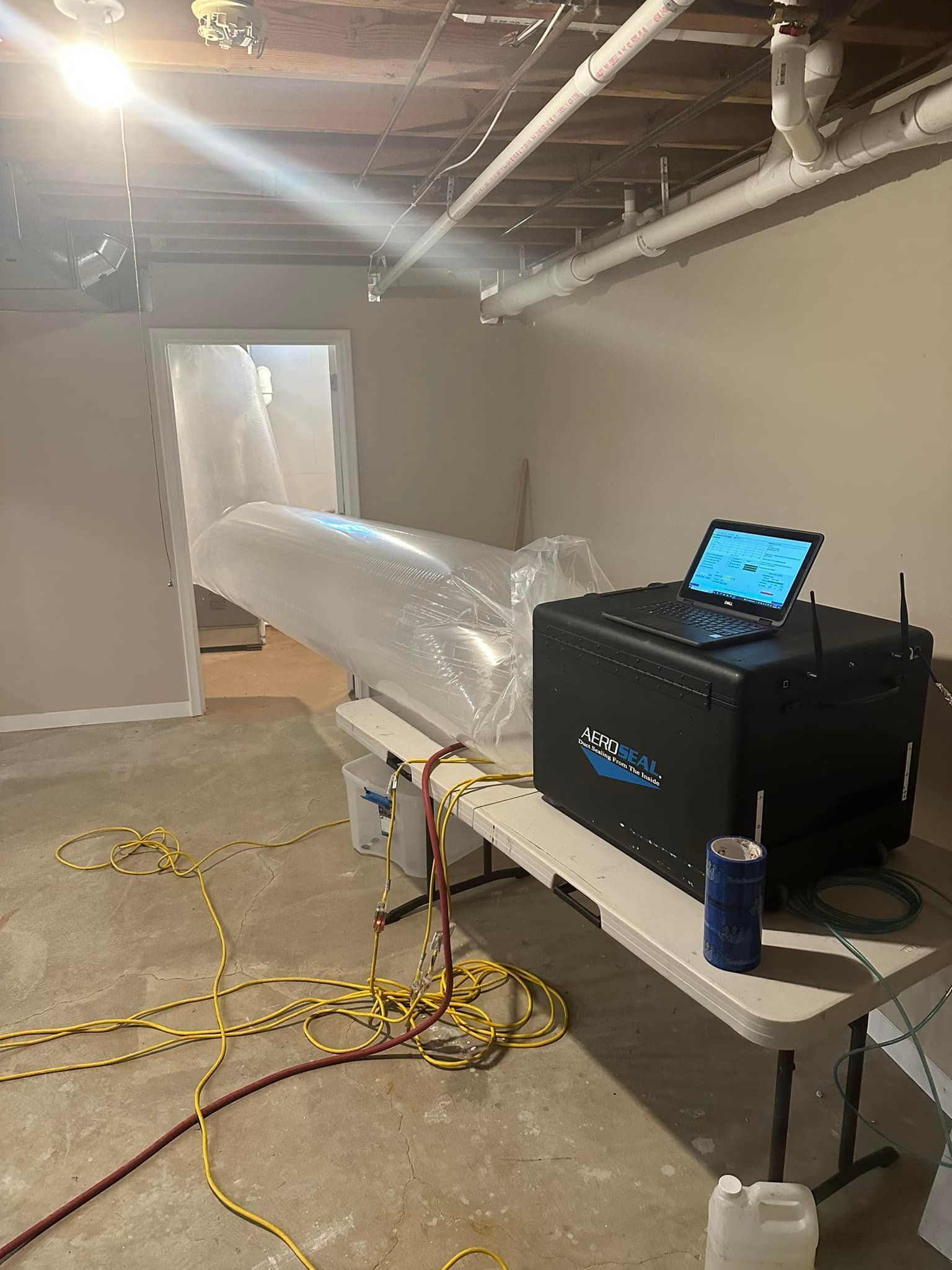 A laptop computer is sitting on top of a table in a basement.