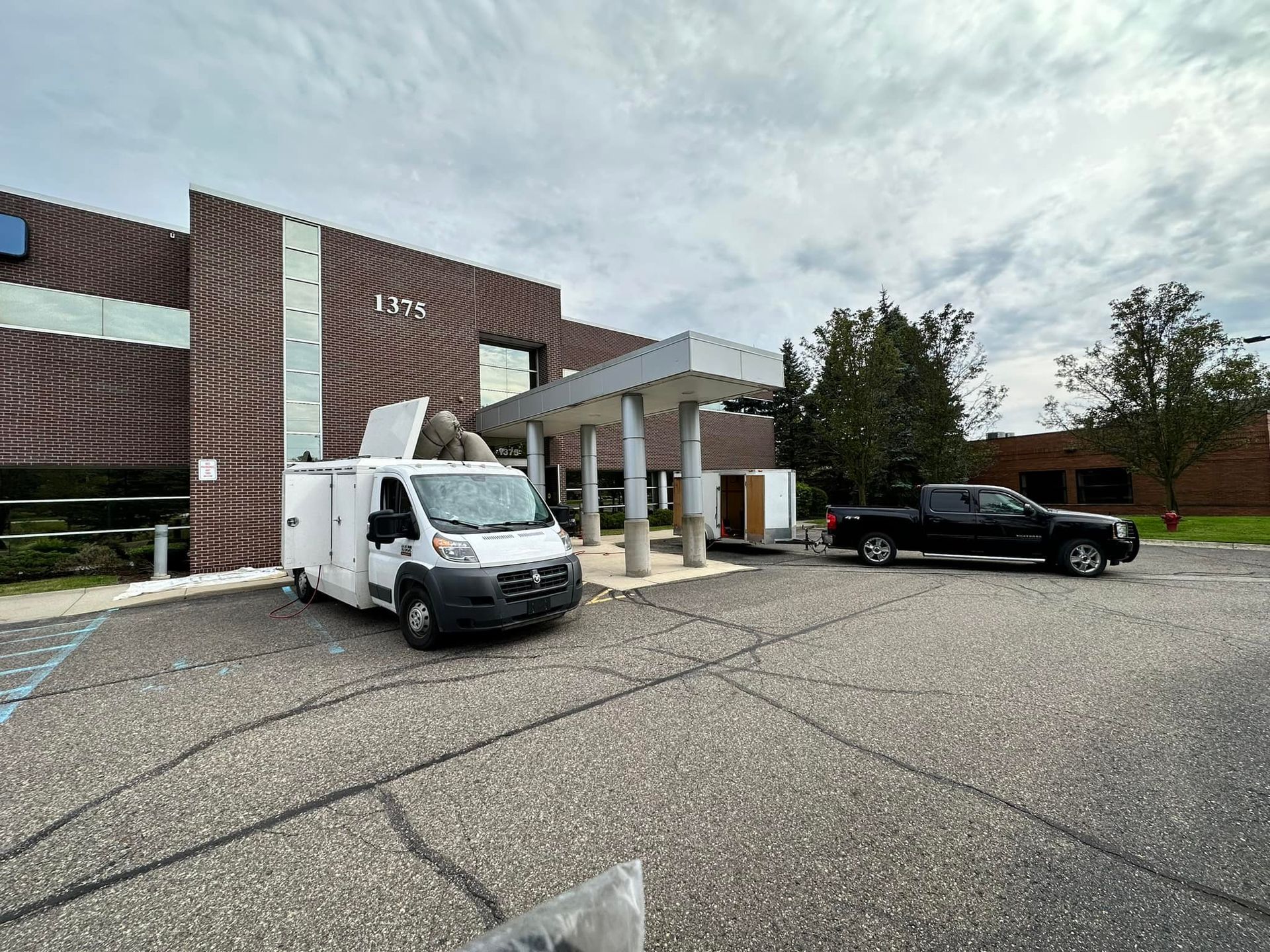 A white van and a black truck are parked in front of a building.