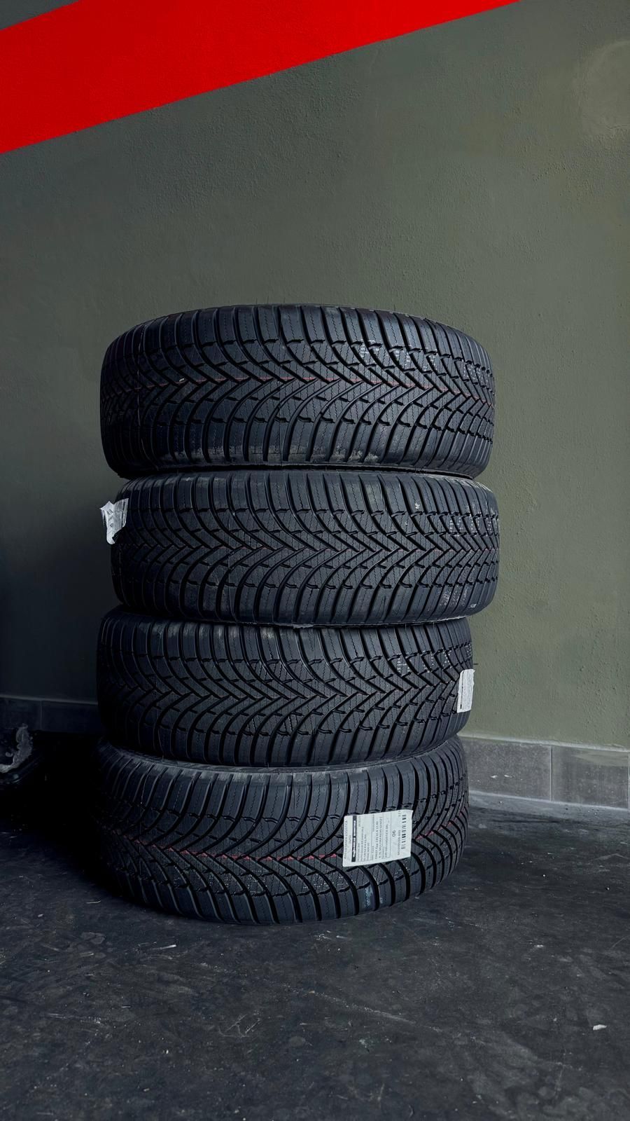 Pila di quattro nuovi pneumatici invernali con battistrada scuro.
