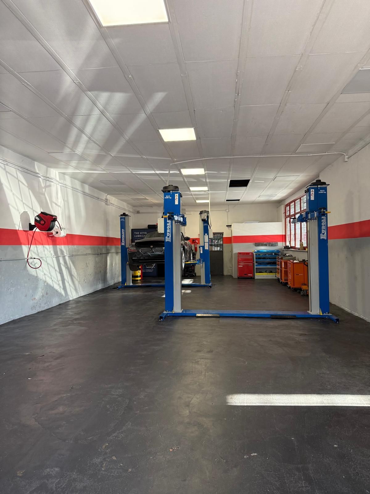 Un ascensore per auto in un garage. Ascensore blu e grigio. Pareti bianche con accenti rossi.