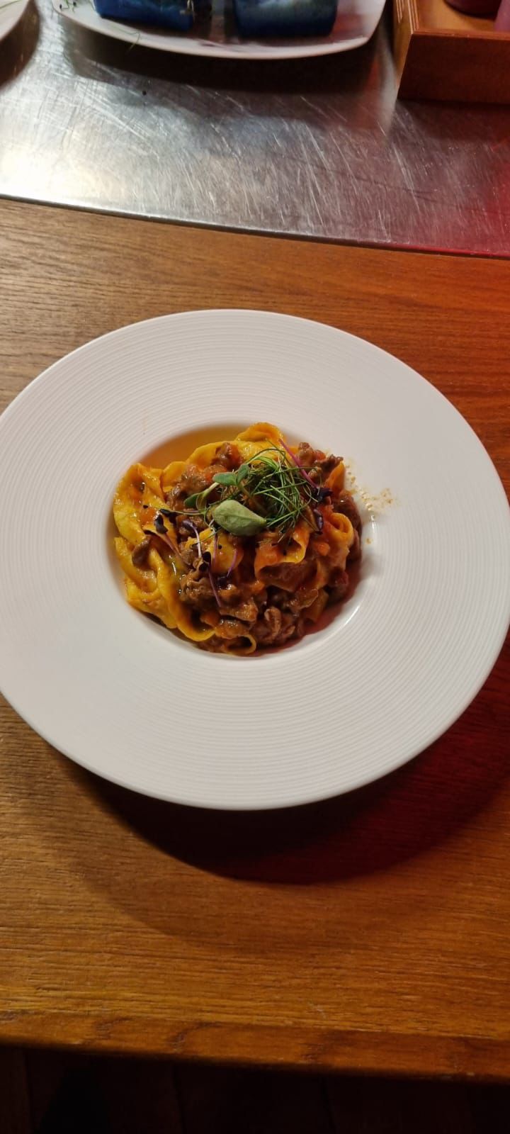 Piatto di pasta su un piatto bianco con bordo strutturato, su un tavolo di legno.