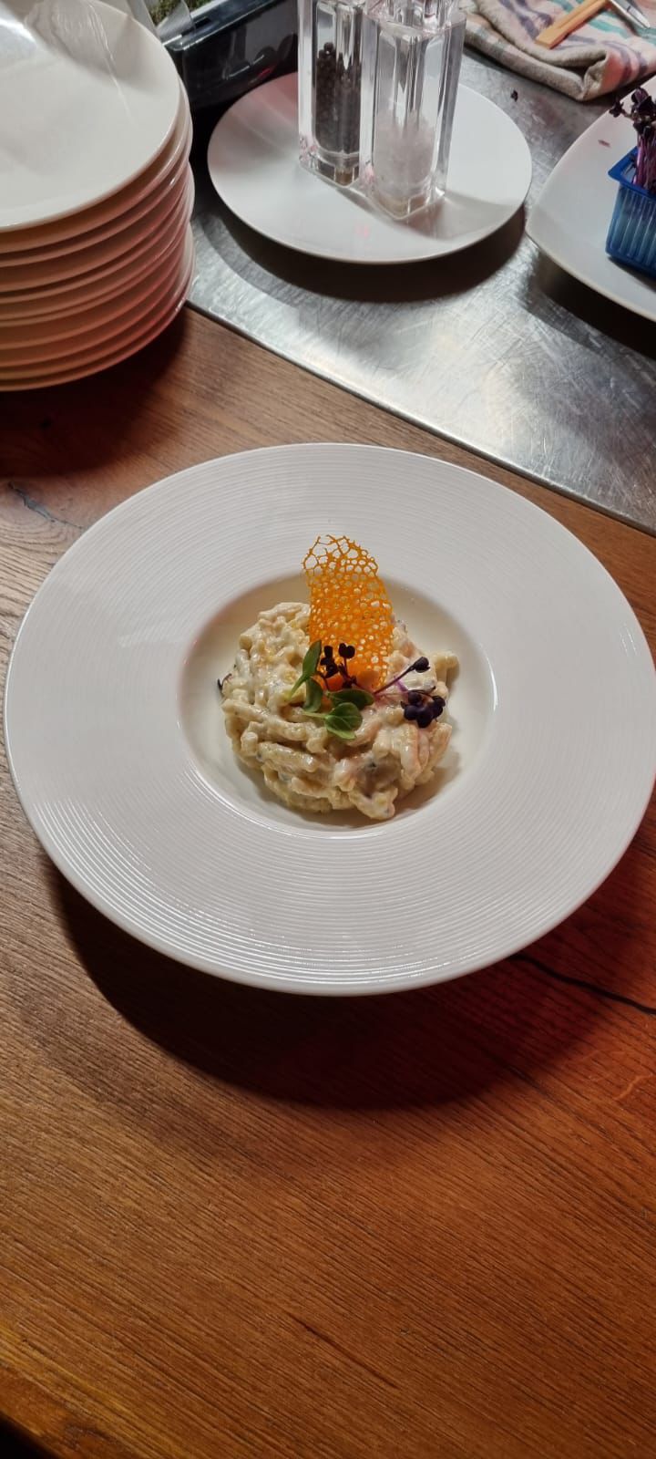 Un piatto di pasta guarnito con caviale su un tavolo di legno.