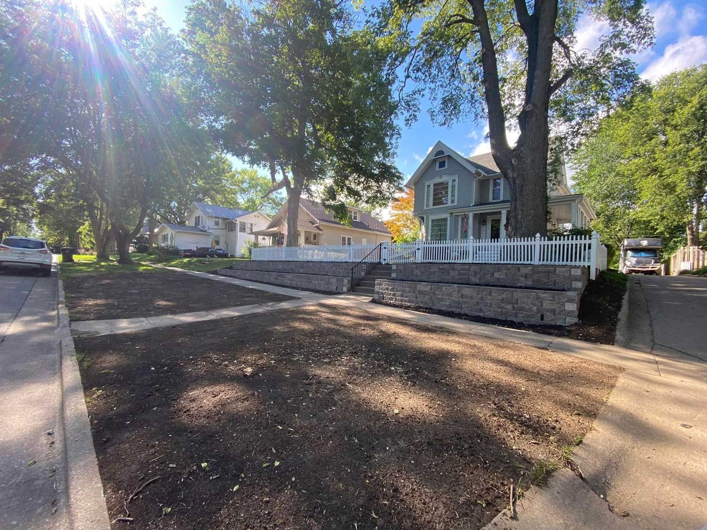 A man is mowing a lush green lawn in front of a house.