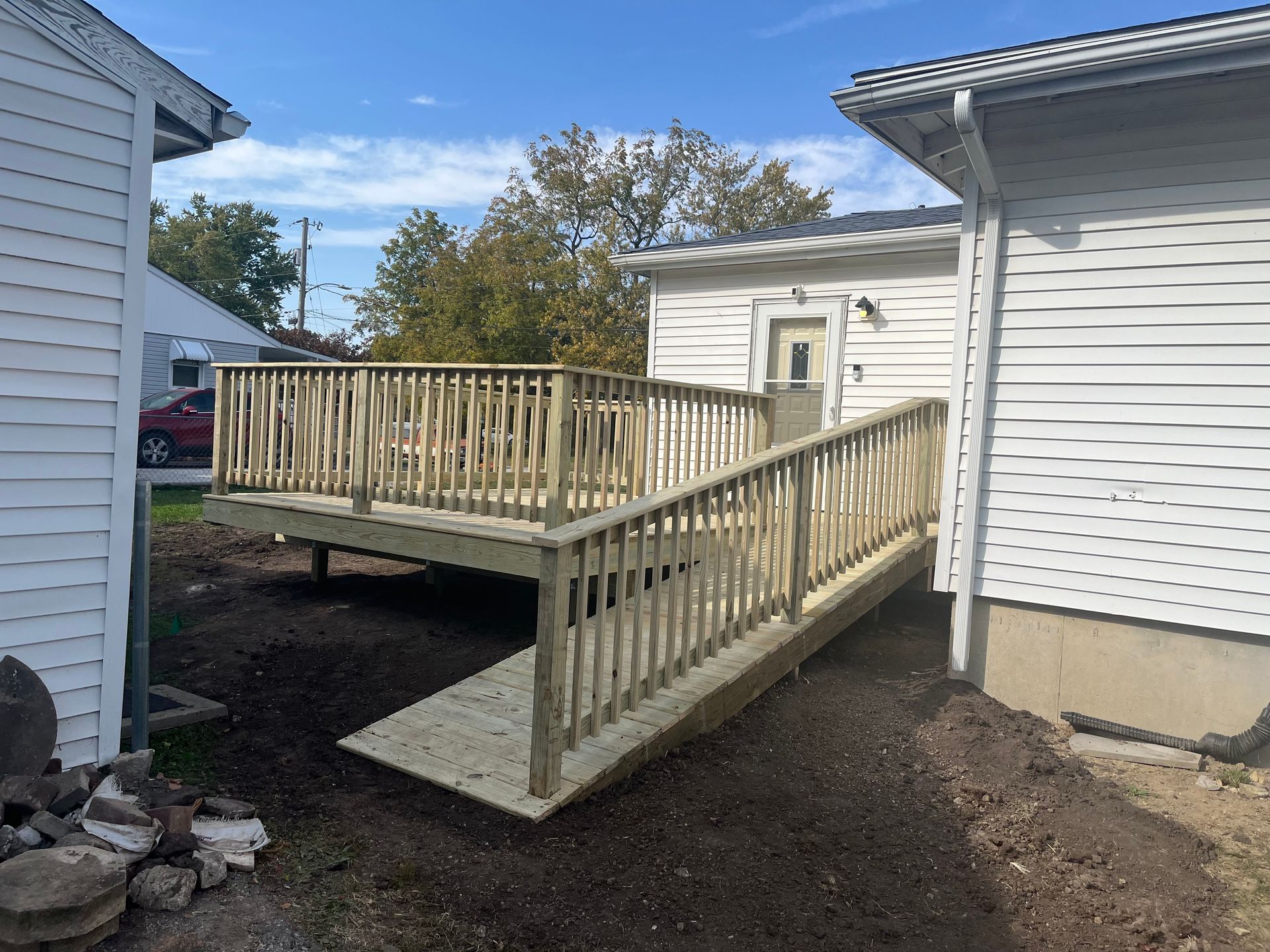 A wooden deck with a ramp between two houses.