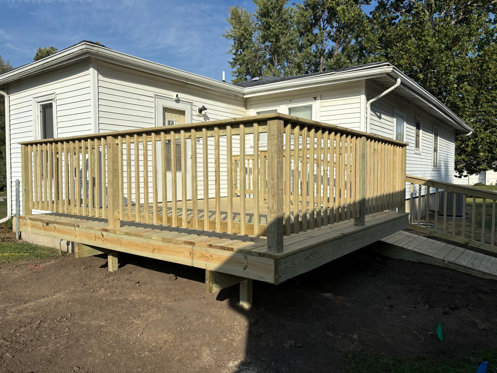 A wooden deck is sitting in front of a white house.