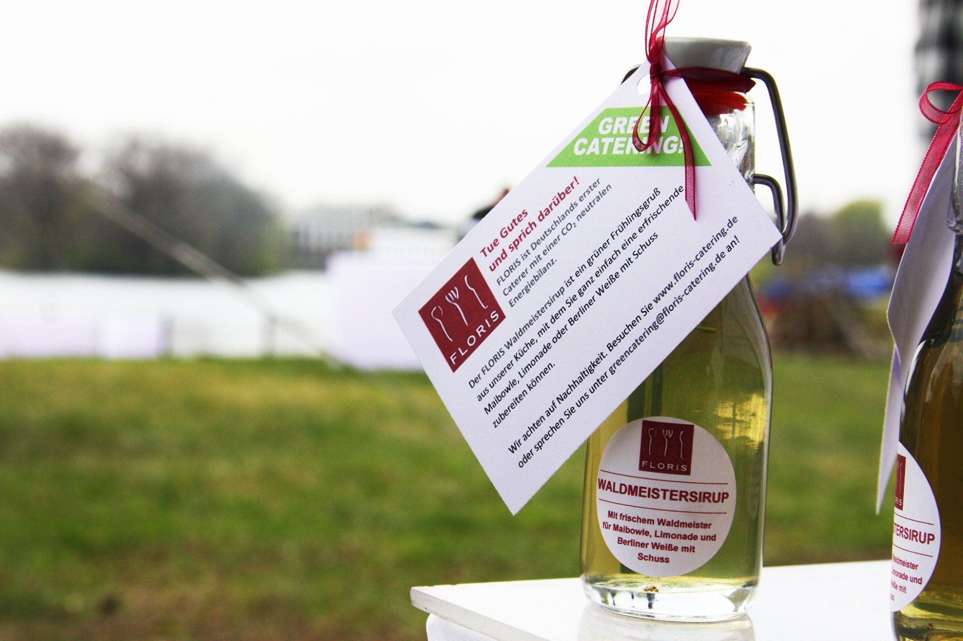 Mit Öl gefüllte Glasflasche mit Bügelverschluss.Grüne Wiese im Hintegrund