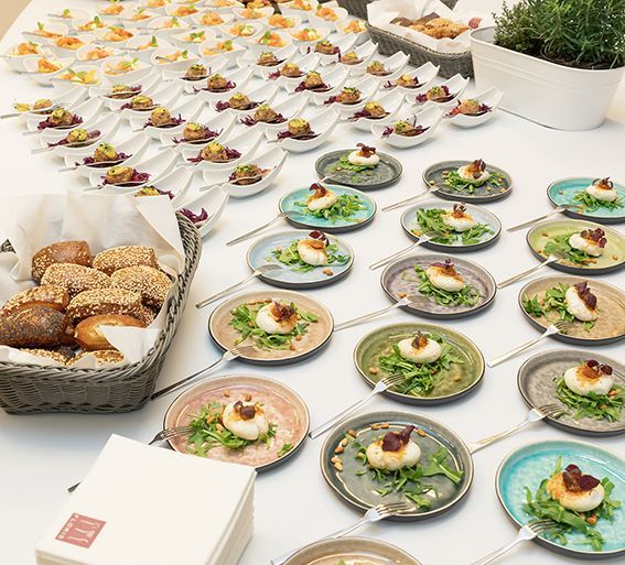 Viele verschiedene Speisenteller auf einem Buffet: Geflämmter Ziegenkäse auf Rucola-Bett mit Honig.  gefüllter Brotkorb