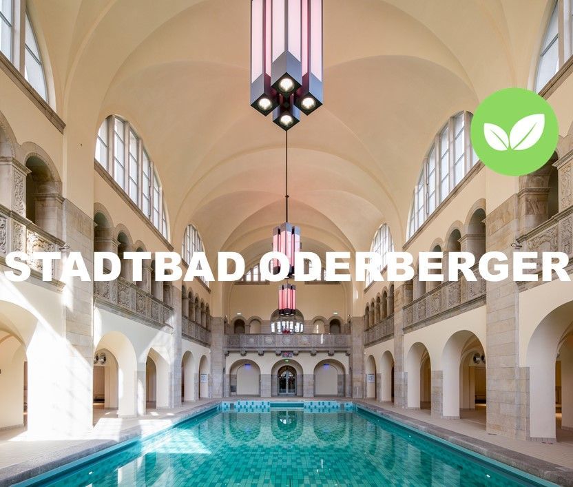 Locationbild des Stadtbades Oderberger. Blick in die Schwimmhalle mit Pool. Mit Logo Green Location